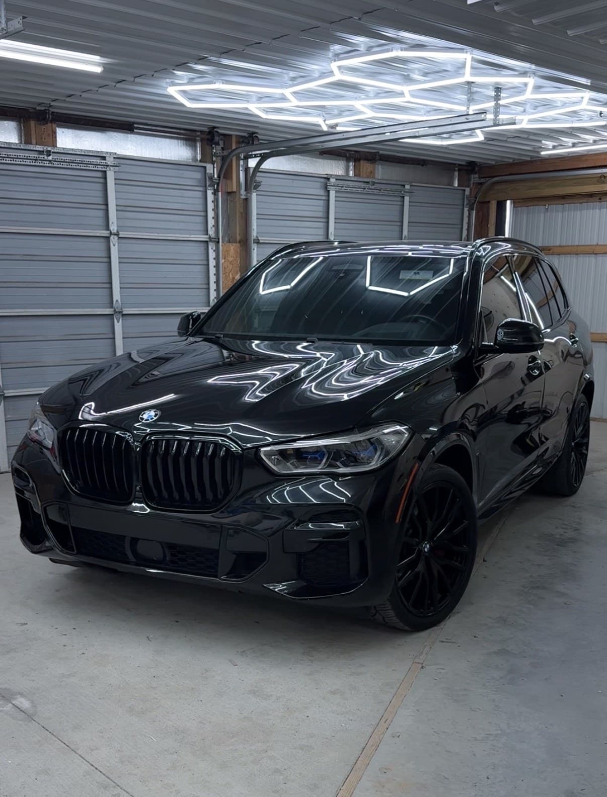 A customer’s black BMW X5 detailed and parked under the hex lighting in the Eagle Pressure bay