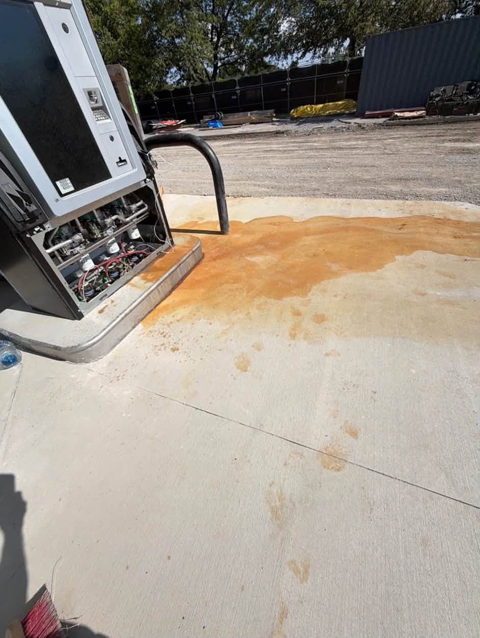 Rust staining spread across a new fuel-island pad before commercial pressure washing