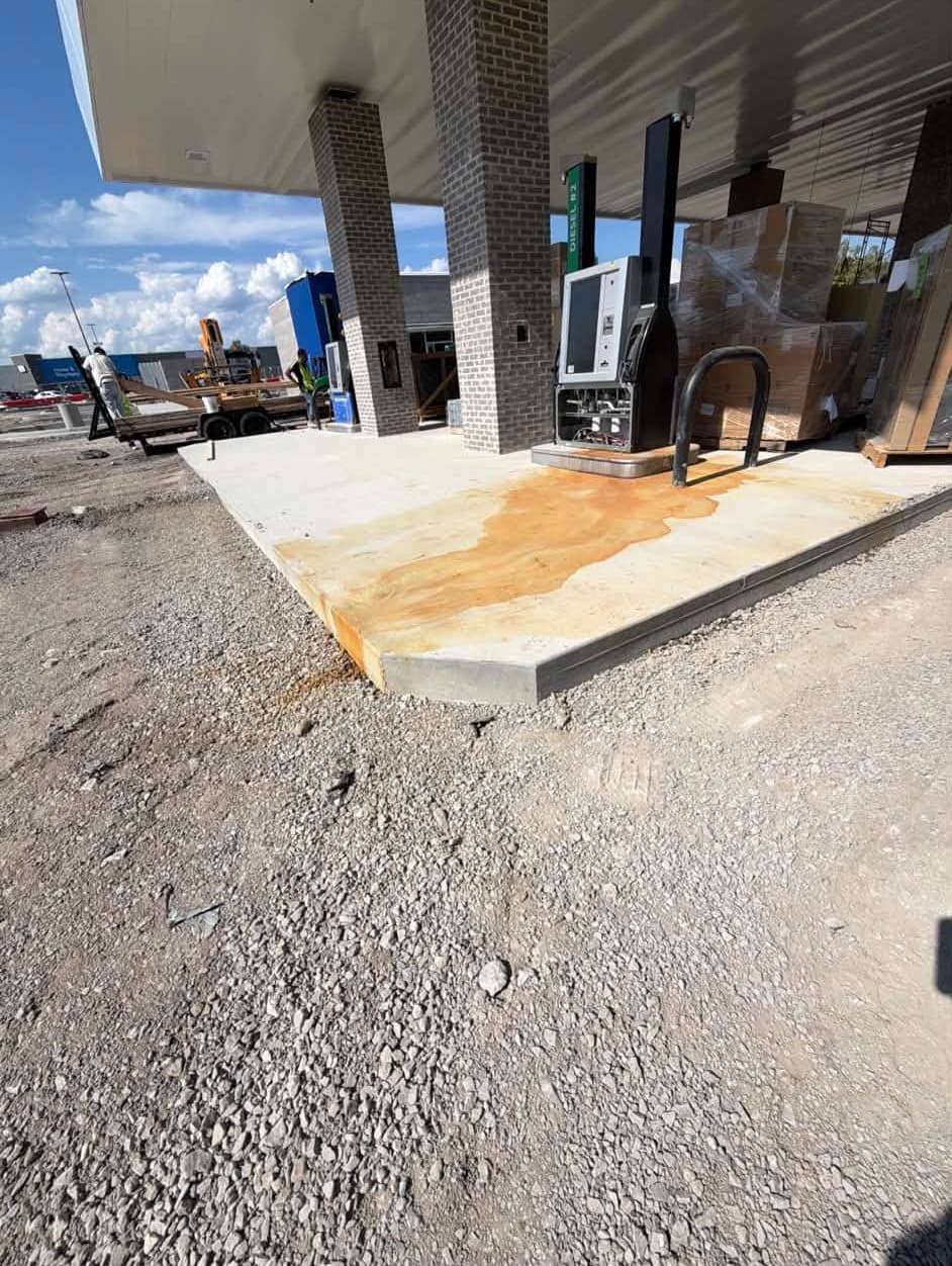 A rust-stained fuel-island pad under a new canopy before commercial pressure washing