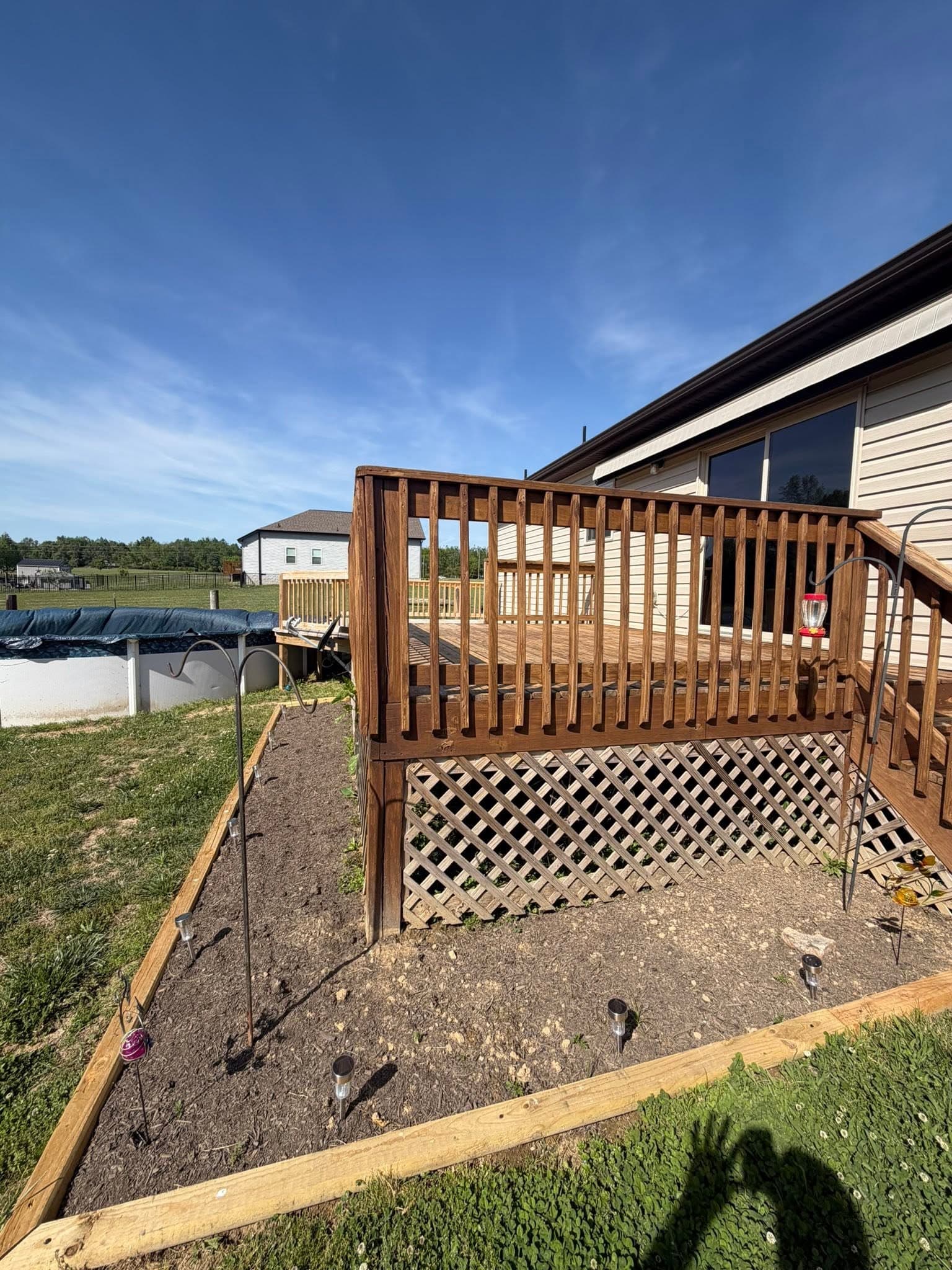 A stained wooden deck with lattice skirting after deck staining