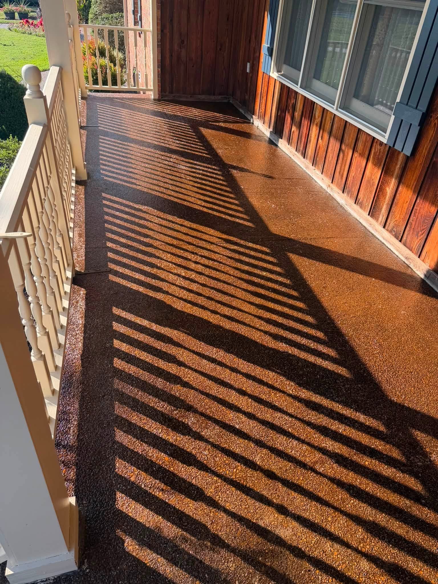 A covered exposed-aggregate porch floor with a deep finish after sealing, the same process as driveway sealing