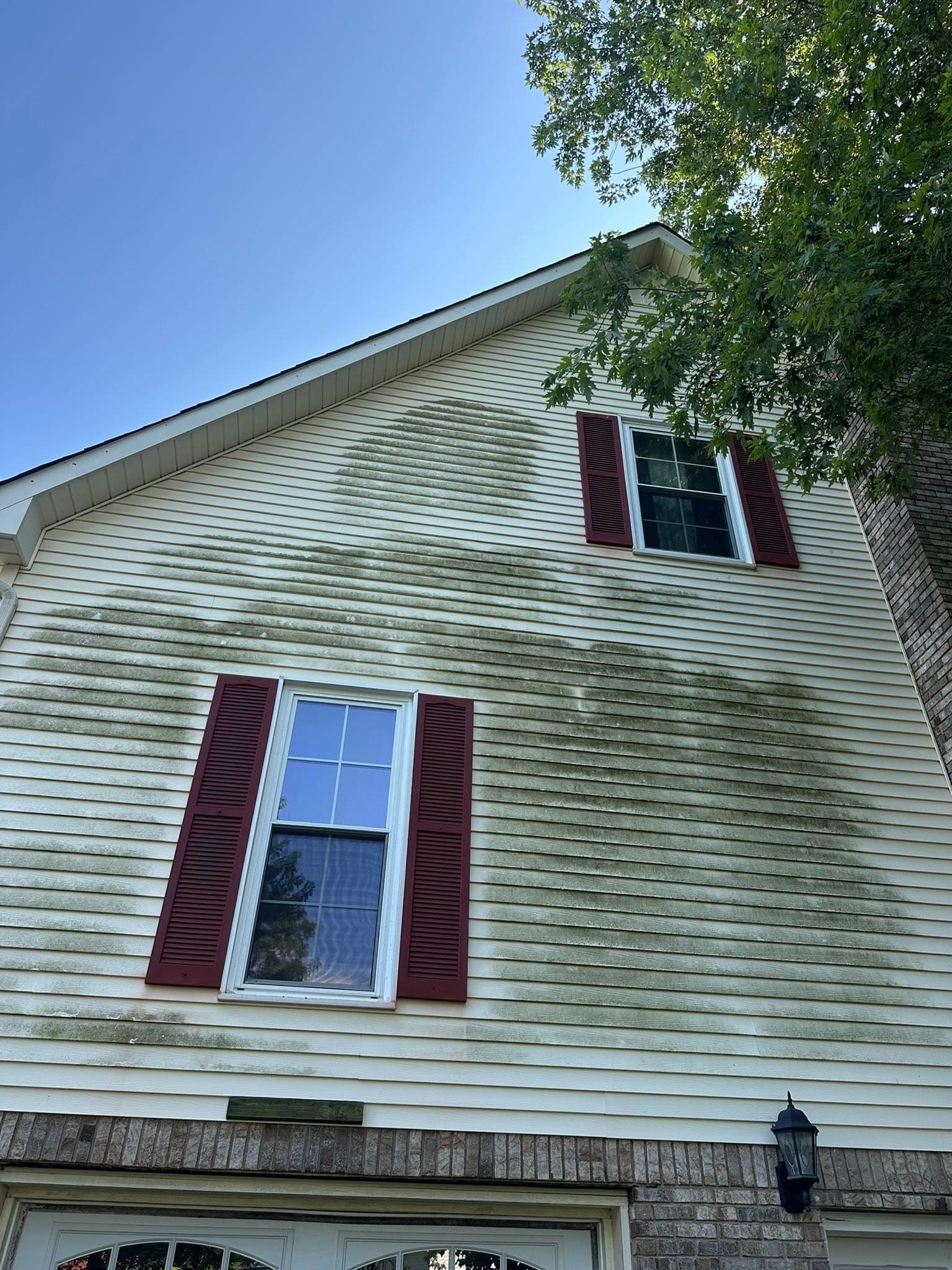 A garage gable streaked with green algae before a house wash