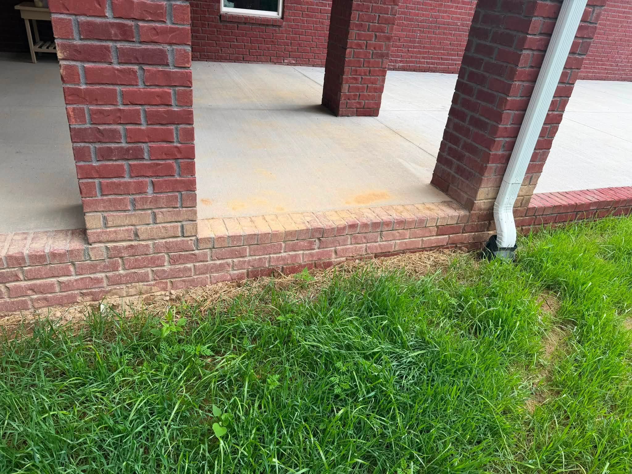 Faded brick knee wall and porch pillars before a brick and porch house wash