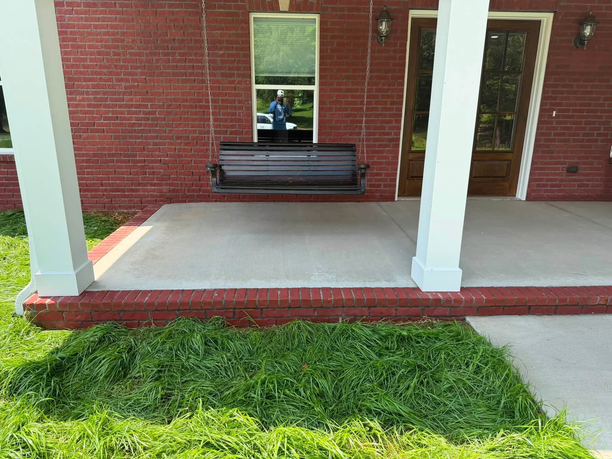 A covered brick porch and concrete slab after a house wash