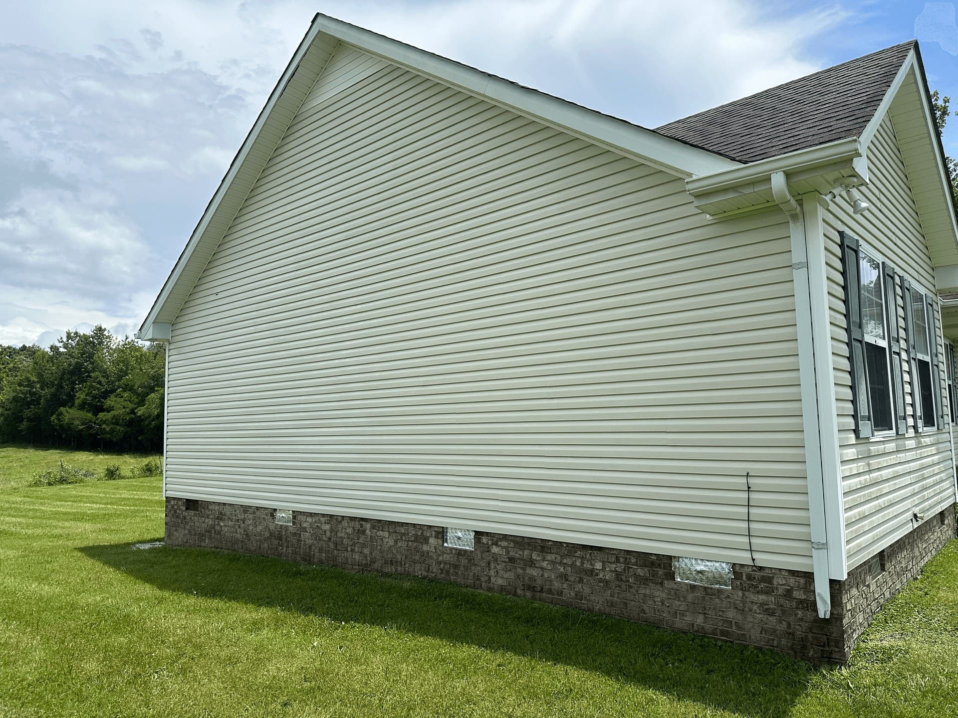 The same house siding cleaned back to its original colour after a soft wash
