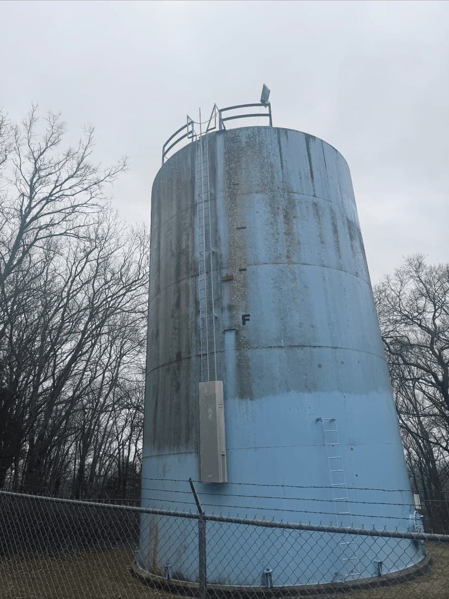 A weathered metal storage tank before pressure washing