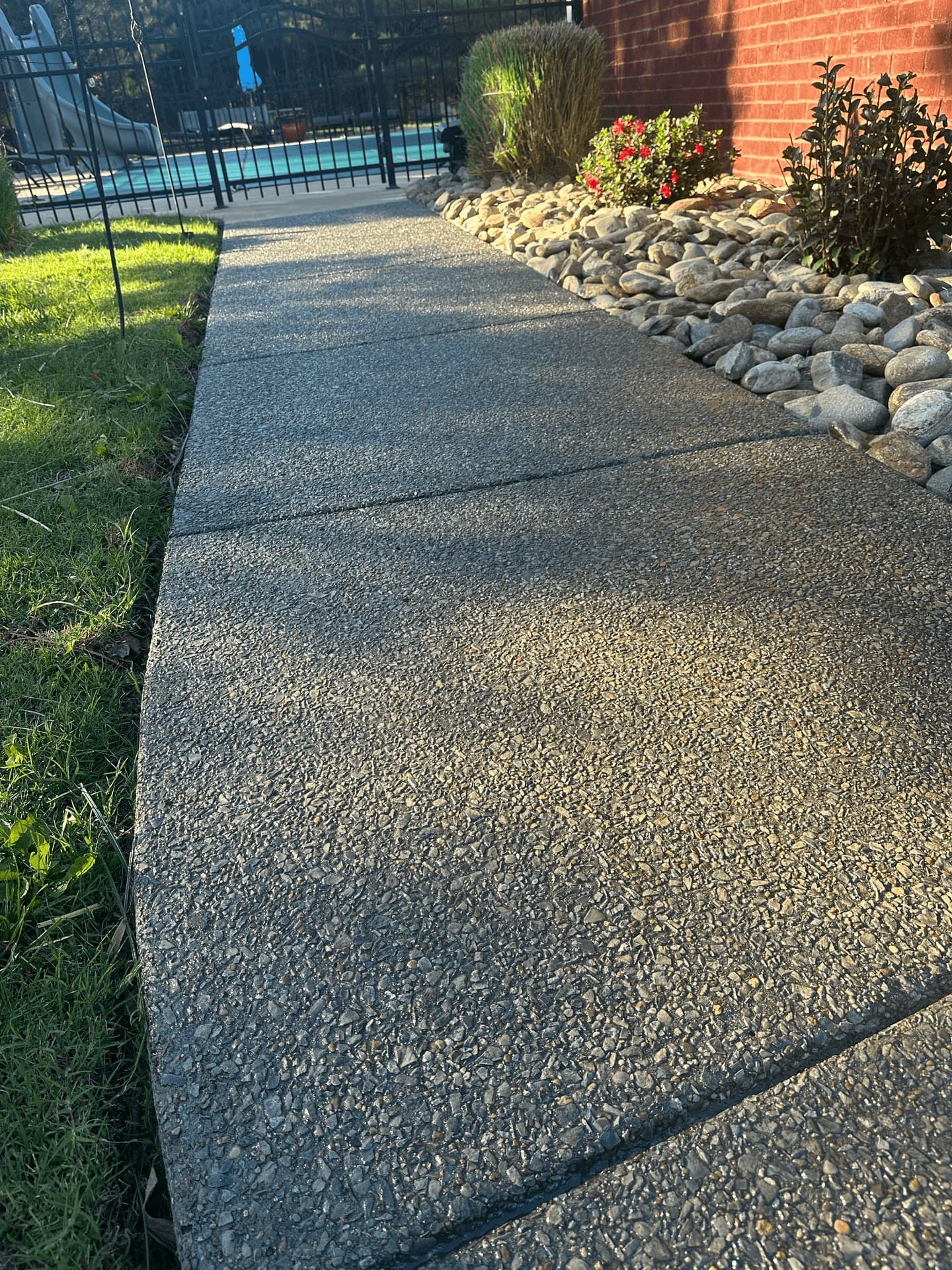 A washed concrete walkway running alongside a planted border